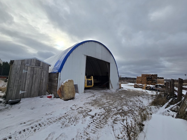 snow covered structure featuring an outbuilding and an outdoor structure