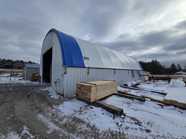 snow covered structure featuring an outbuilding and a pole building