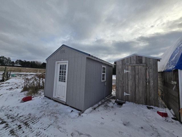 snow covered structure with a storage unit and an outdoor structure