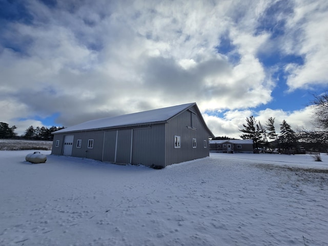 exterior space featuring a detached garage, an outdoor structure, and a pole building