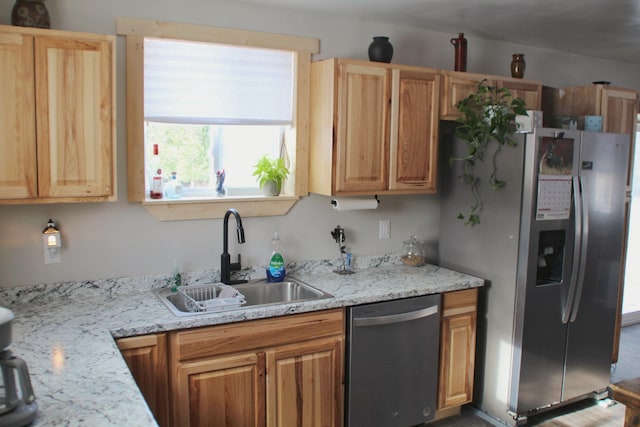 kitchen featuring a sink, light stone counters, and stainless steel appliances