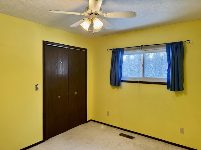 unfurnished bedroom featuring visible vents, baseboards, light colored carpet, a closet, and a textured ceiling