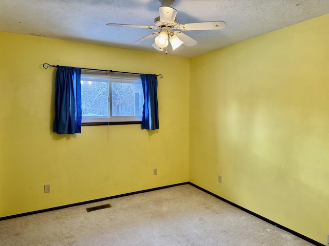 unfurnished room with visible vents, a textured ceiling, carpet flooring, baseboards, and ceiling fan