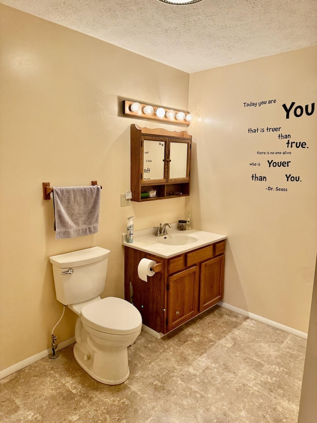 bathroom with baseboards, toilet, vanity, and a textured ceiling