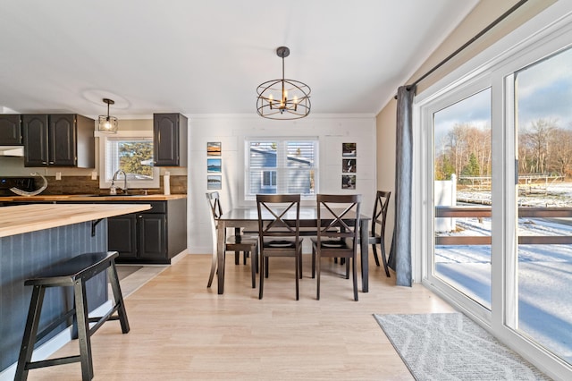 dining area with light wood-style floors and an inviting chandelier