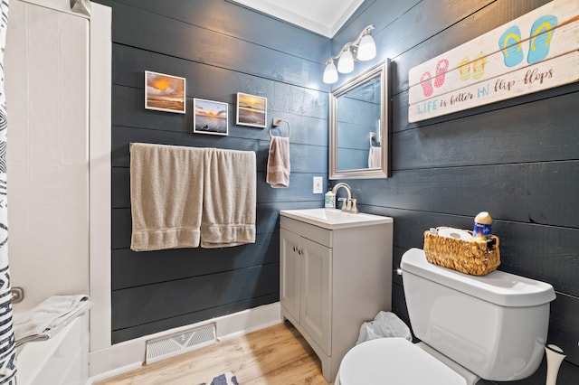 bathroom with visible vents, wood walls, toilet, wood finished floors, and vanity