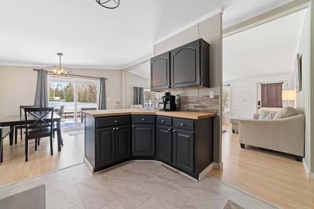 kitchen with visible vents, a peninsula, vaulted ceiling, wood counters, and a chandelier