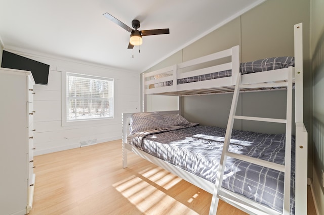 bedroom featuring a ceiling fan, vaulted ceiling, wood finished floors, and visible vents