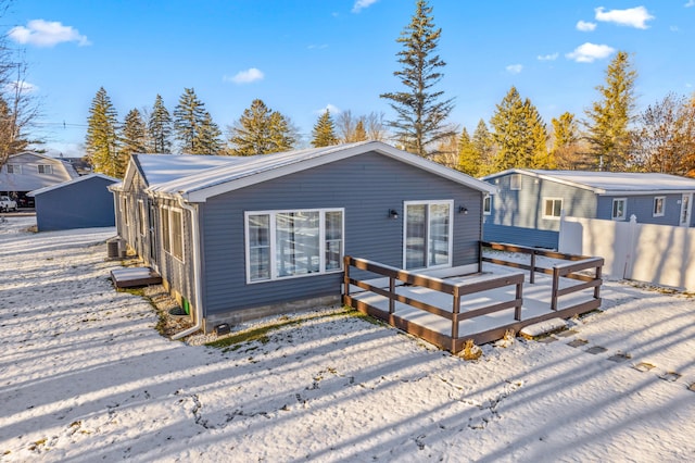 snow covered house featuring central air condition unit and a wooden deck