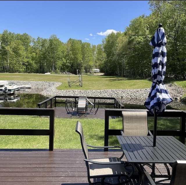 wooden deck featuring outdoor dining space and a lawn