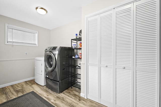 washroom with light wood-style flooring, separate washer and dryer, wainscoting, and laundry area