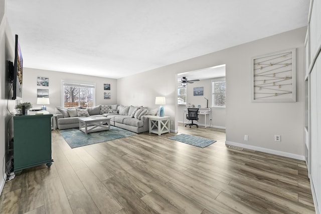 living room featuring ceiling fan, baseboards, and wood finished floors