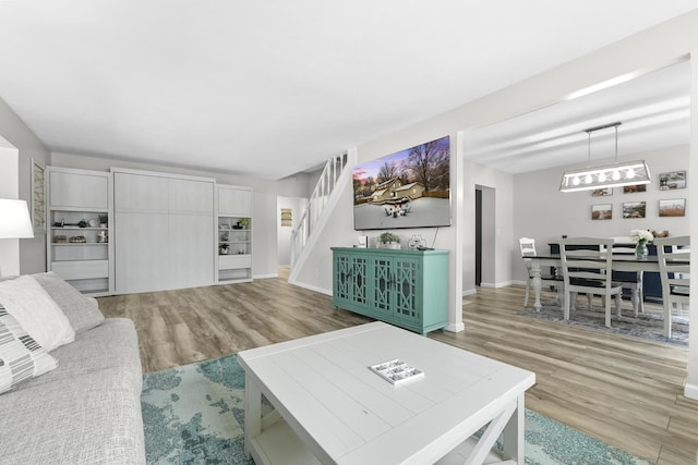 living area with stairs, wood finished floors, and baseboards