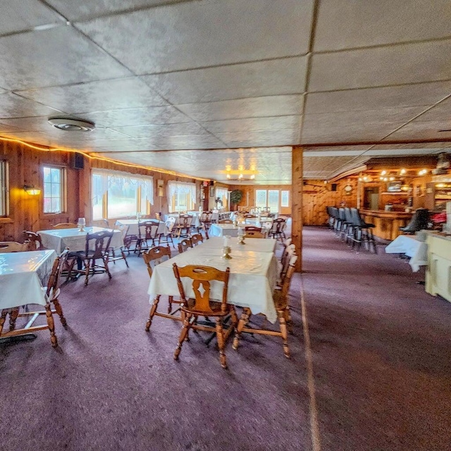 dining room featuring carpet flooring and wood walls