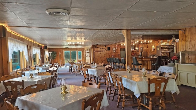 dining space with wooden walls and carpet