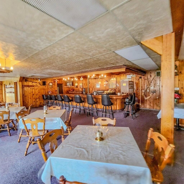 dining room featuring a community bar and wood walls