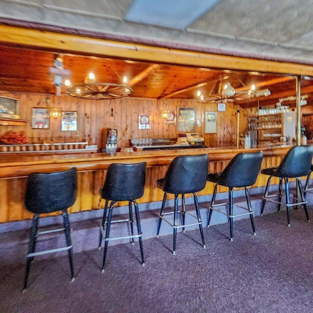 bar featuring wood walls, a dry bar, lofted ceiling with beams, and carpet