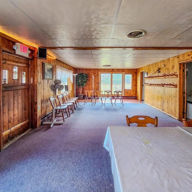 carpeted dining area with visible vents and wood walls