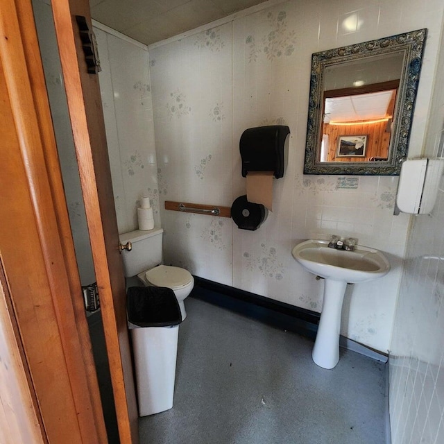 bathroom featuring toilet, baseboards, and a sink