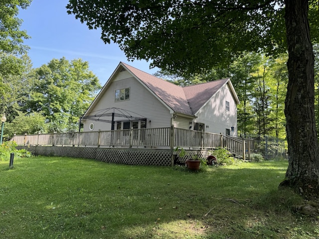 back of house with a lawn, roof with shingles, and a deck