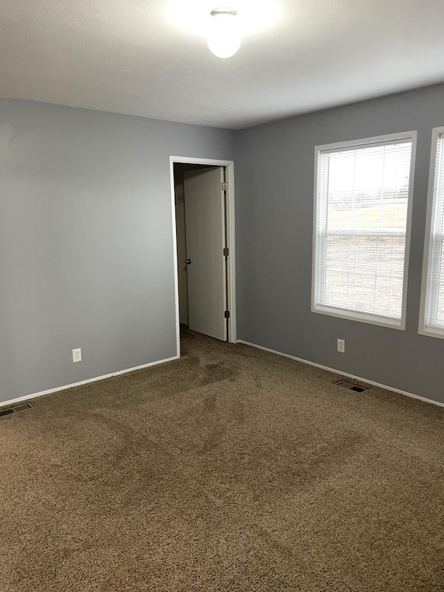 empty room with visible vents, baseboards, and carpet