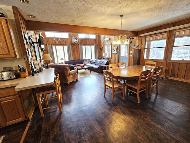 dining area with wooden walls, dark wood-style flooring, and a textured ceiling