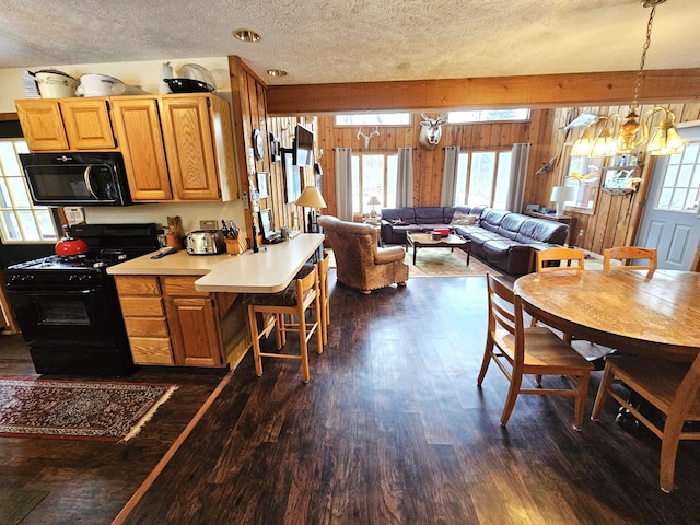 dining room featuring plenty of natural light, a textured ceiling, wooden walls, and dark wood-style flooring