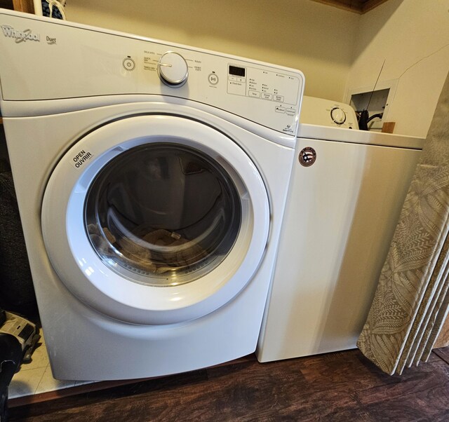 clothes washing area with laundry area, washing machine and dryer, and wood finished floors