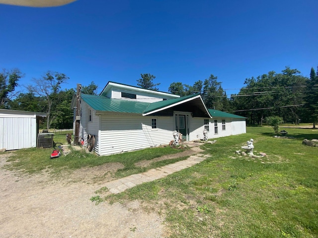 view of front of house featuring central AC unit, metal roof, and a front yard