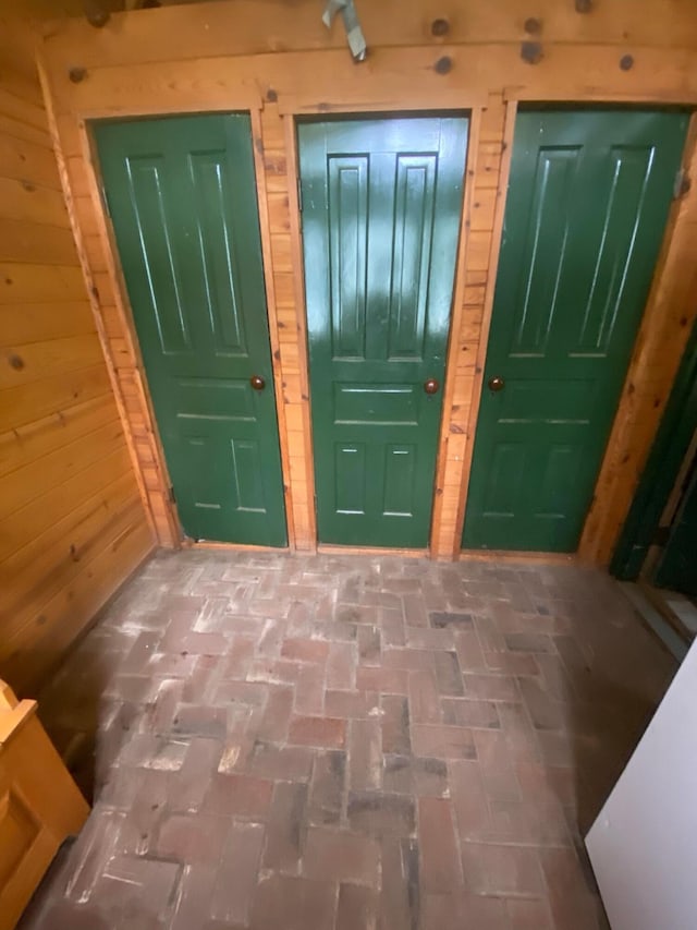 foyer entrance with brick floor and wood walls