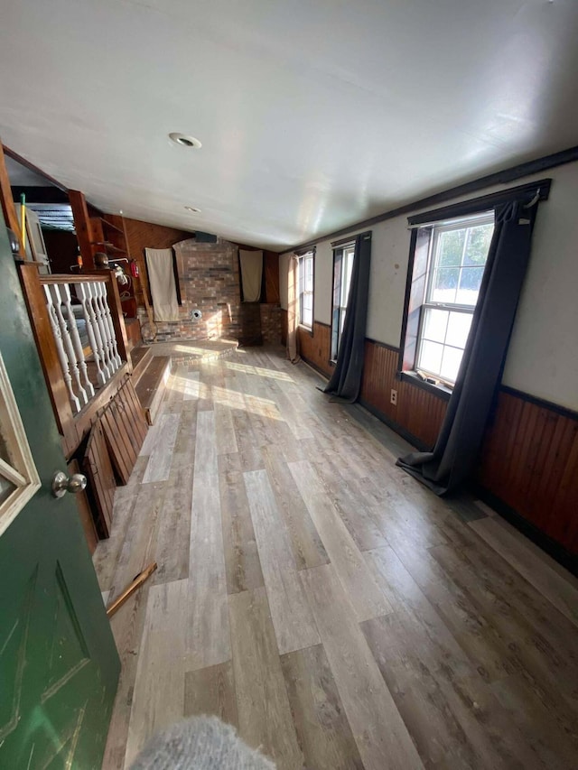 unfurnished living room featuring wooden walls, wood finished floors, and wainscoting