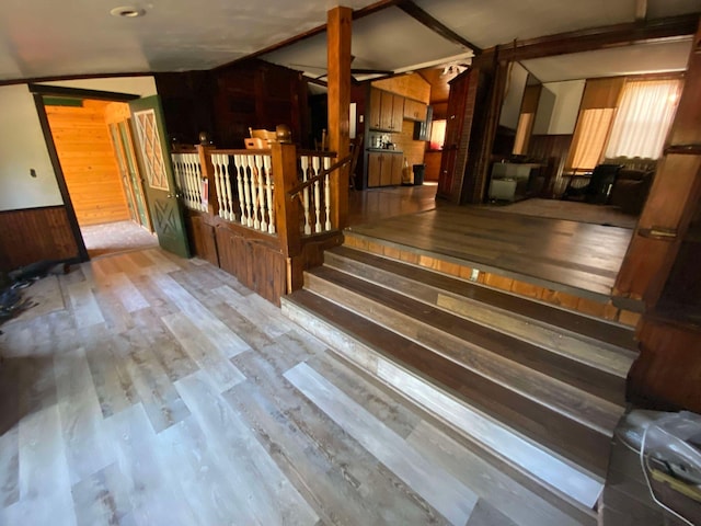 stairs featuring a wainscoted wall, wood walls, and wood finished floors