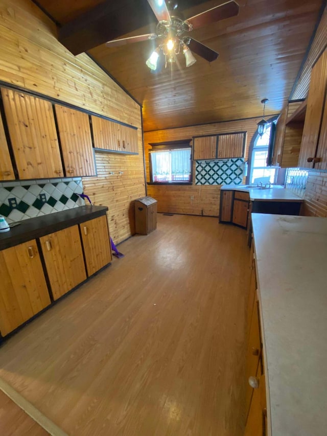 kitchen featuring wooden walls, light wood finished floors, lofted ceiling with beams, ceiling fan, and wood ceiling