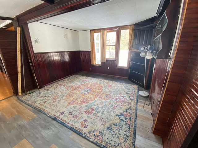 foyer entrance featuring a wainscoted wall, wooden walls, and wood finished floors