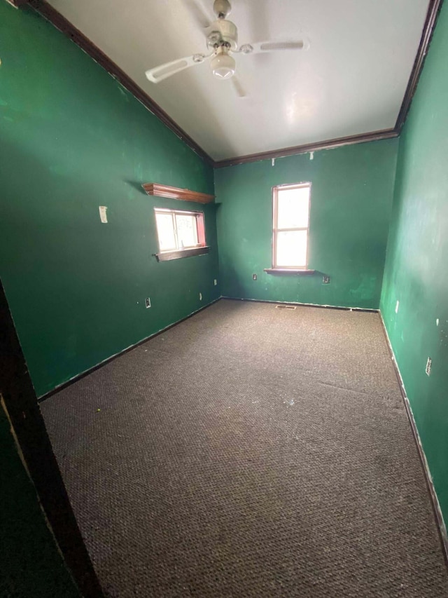 unfurnished room with crown molding, baseboards, carpet, vaulted ceiling, and a ceiling fan