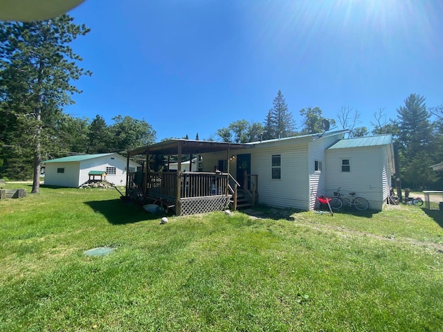 rear view of property with metal roof, a lawn, and a deck