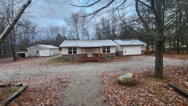 view of front of property featuring an attached garage, stone siding, and driveway