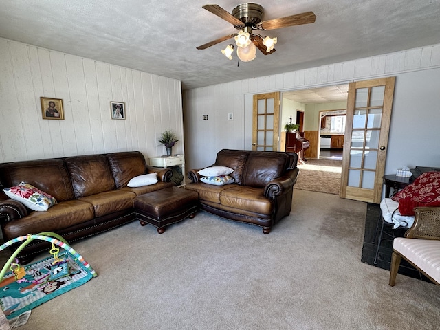 living area featuring carpet flooring, french doors, a textured ceiling, and ceiling fan