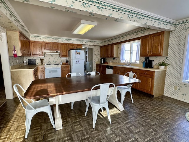 kitchen with wallpapered walls, white appliances, baseboards, and brown cabinets