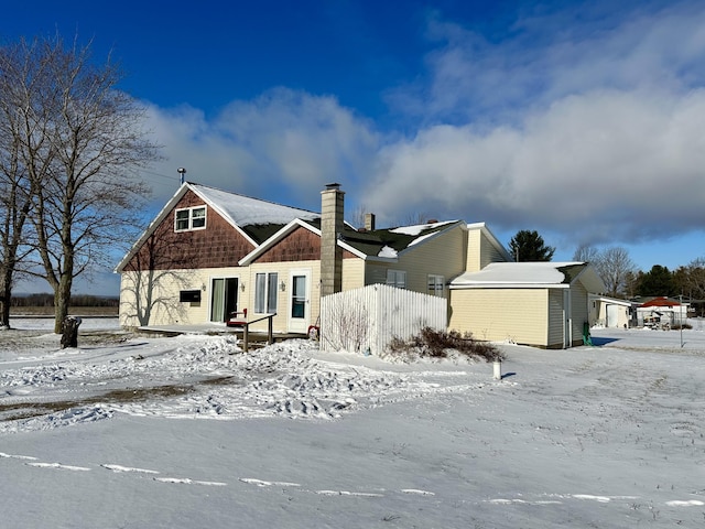 view of front of home with an outdoor structure, a chimney, and fence