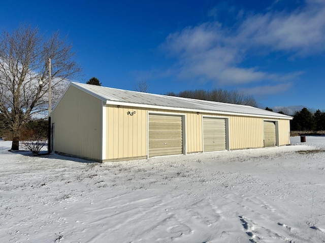 snow covered garage with a detached garage