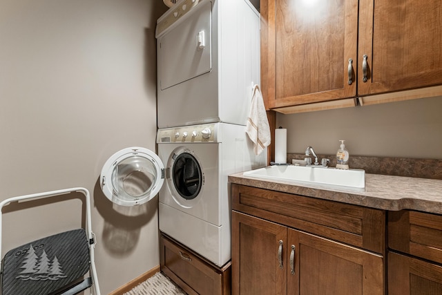 laundry area featuring stacked washer and dryer, cabinet space, and a sink