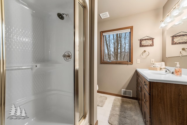 bathroom with vanity, a shower stall, baseboards, and visible vents