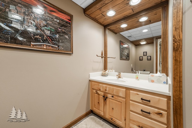 bathroom featuring a drop ceiling, recessed lighting, vanity, and baseboards