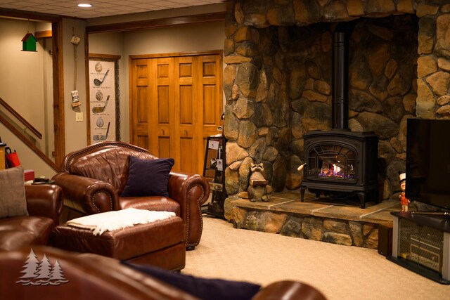 carpeted living room with a wood stove and a paneled ceiling