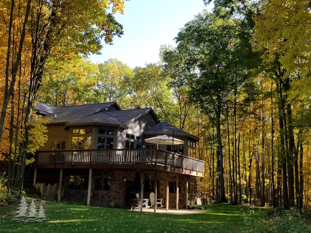 rear view of property featuring stone siding, a lawn, and a deck