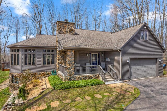 220 Skyview Ct, Lewiston, MI 49756 - view of front facade featuring a porch, asphalt driveway, a shingled roof, and a chimney