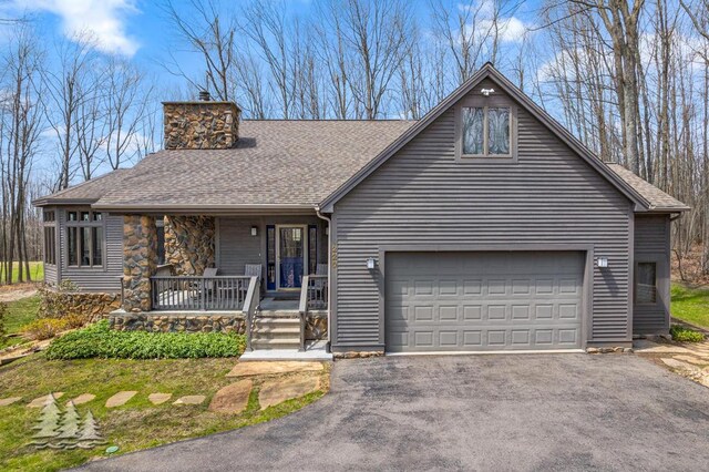 220 Skyview Ct, Lewiston, MI 49756 - view of front facade with a porch, a chimney, driveway, and roof with shingles