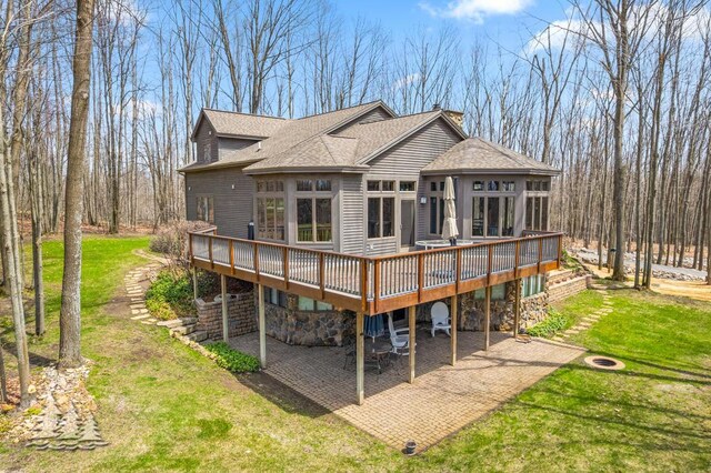 220 Skyview Ct, Lewiston, MI 49756 - rear view of property with roof with shingles, a deck, a patio, a lawn, and stone siding