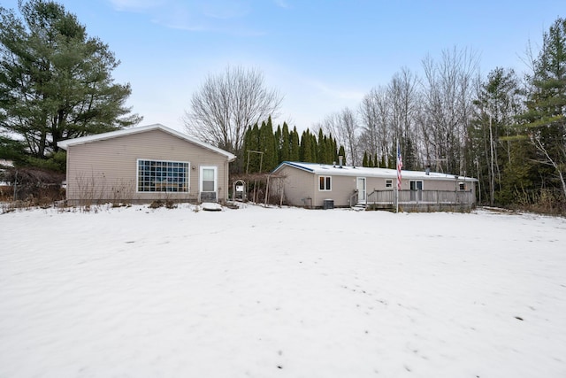 snow covered rear of property with a deck